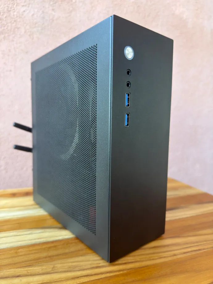 A black Companion computer seen at an angle on a wooden table, showing its ventilated side panel and front ports
